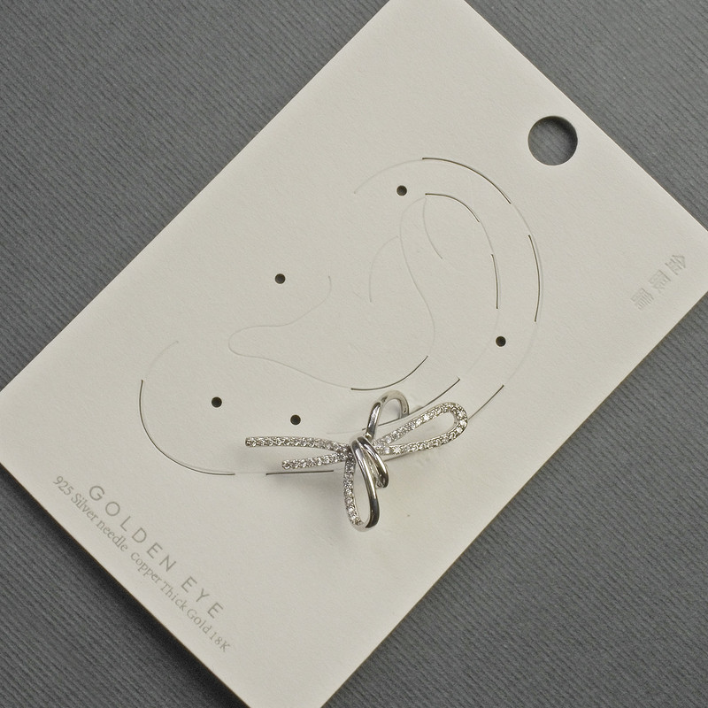 Ohrclip „Schleife“ aus silberfarbenem Metall 17x30 mm ± mit weißen Strasssteinen