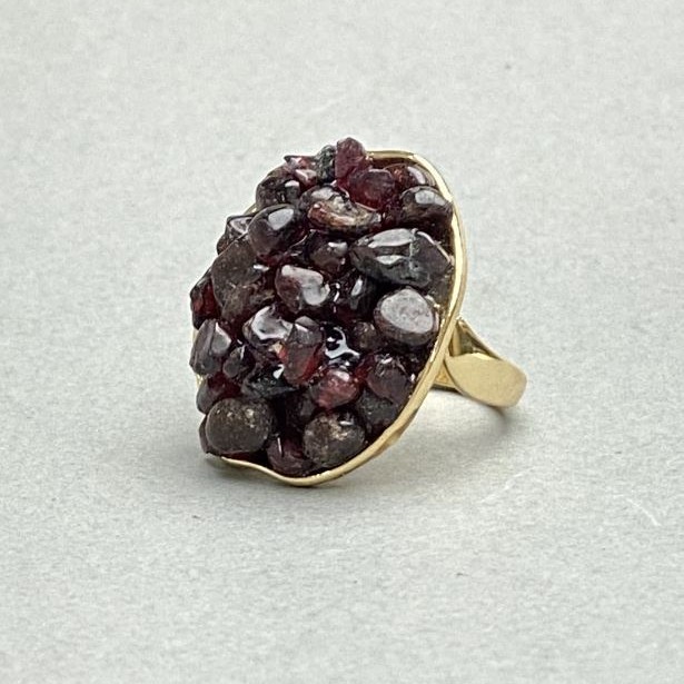 Ring mit Granatkörnchen in glatter Fassung, 30 × 26 mm ±, goldfarbenes Metall, Größe