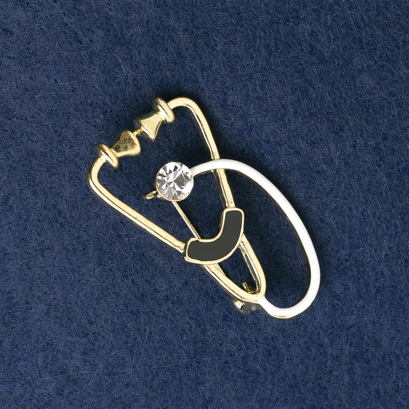 Brosche Stethoskop, Emaille weiß und schwarz, mit weißem Stein, goldenes Metall 43 × 24 mm